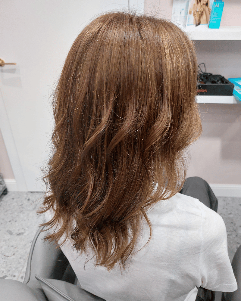 Lekka koloryzacja bronde z miękkimi falami na średniej długości włosach